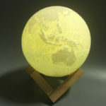 a glowing 3d earth lamp on the wood stand