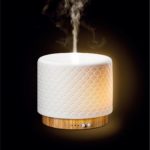 a bamboo base ceramic aroma diffuser is running with mist