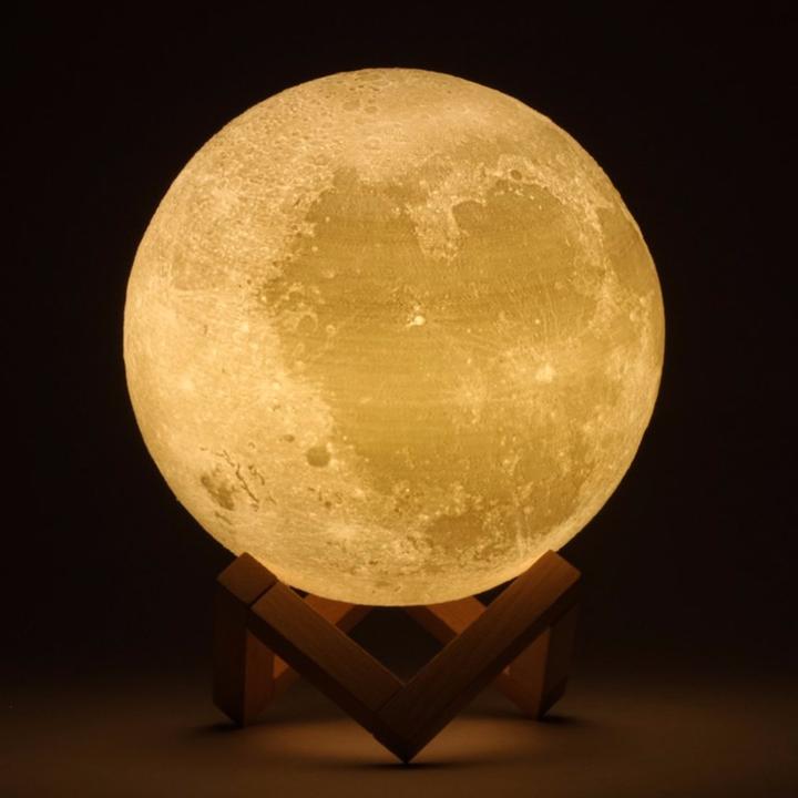 a glowing 3d moon lamp on the stand in the darkness