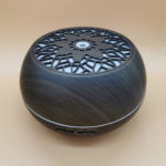 an electric aroma oil diffuser in dark wood color