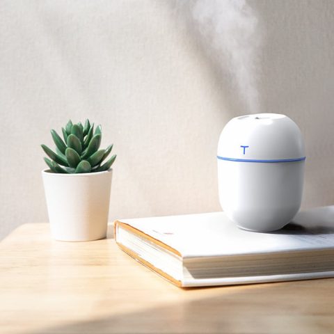 a white color small humidifier for office is runing with mist