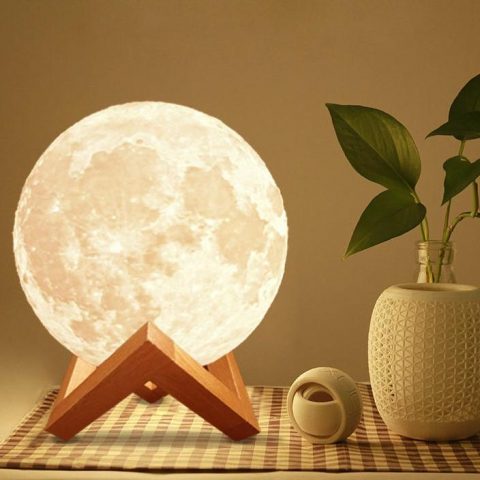 a glowing 3d moon lamp with stand stand on the desk